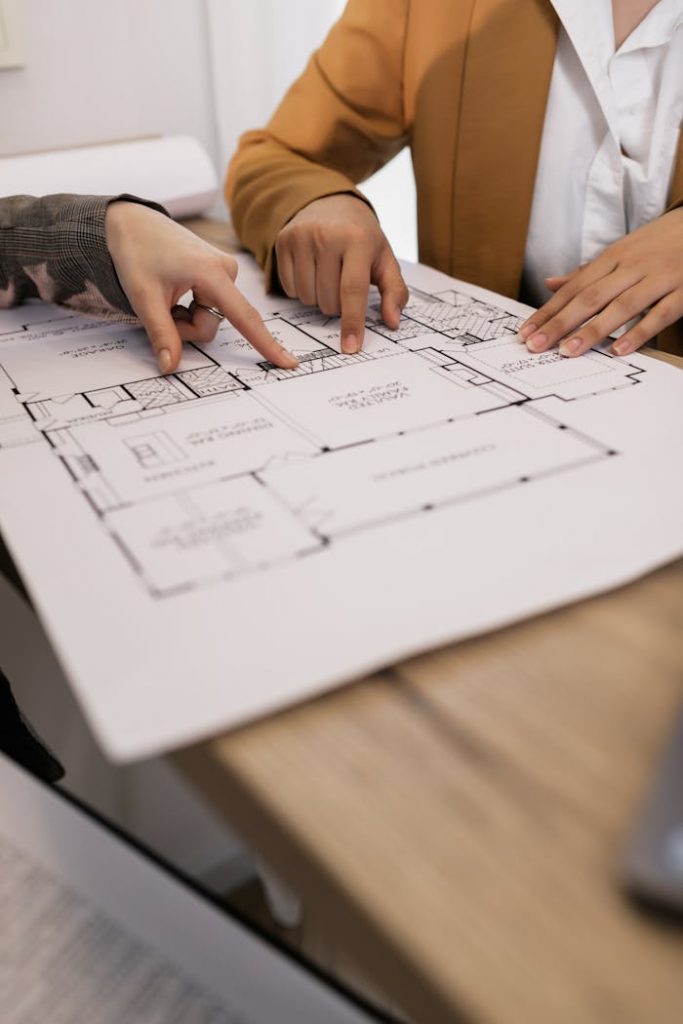 pexels-photo-7642117 Two professionals discussing architectural plans in an office setting.